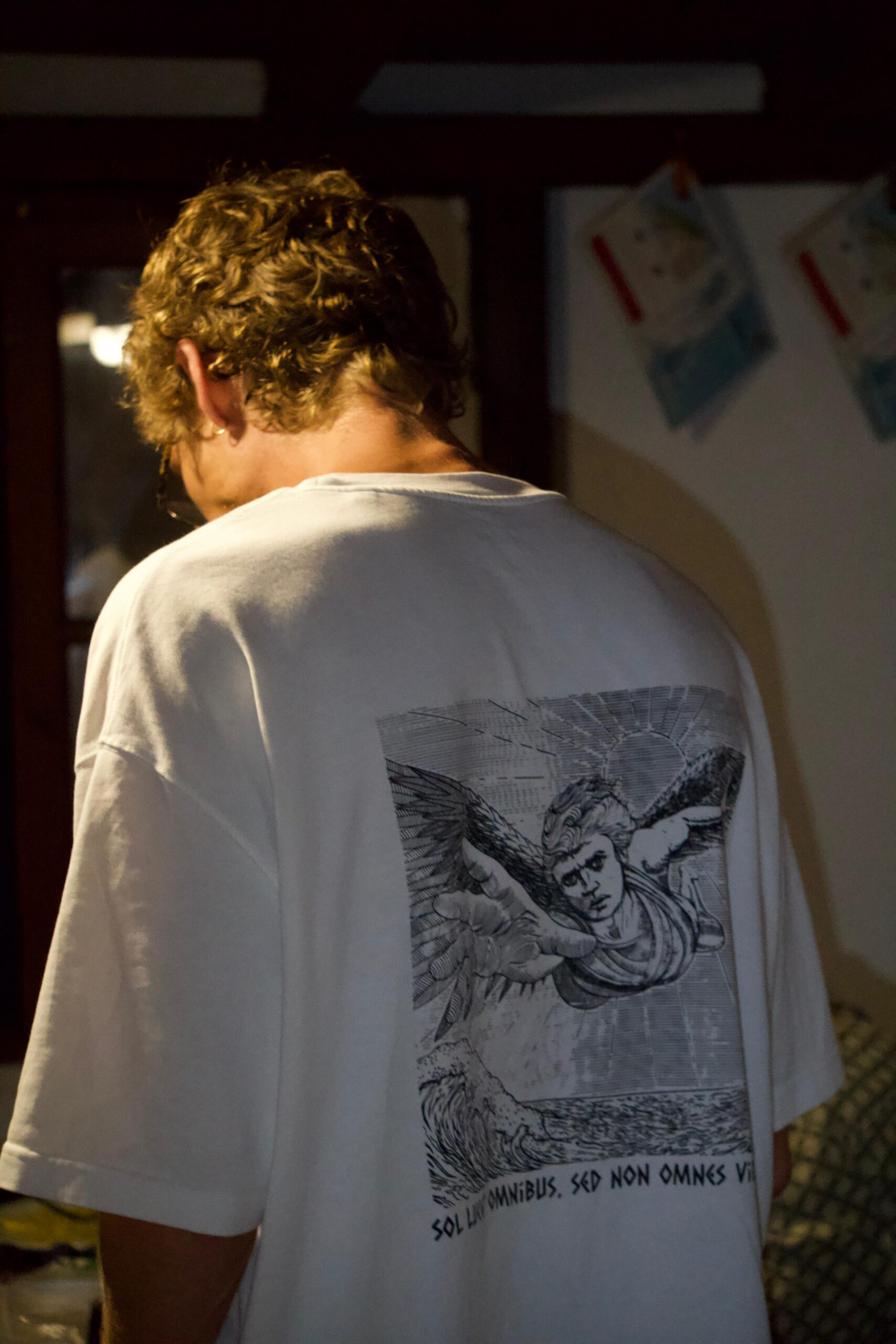 Joven de espaldas vistiendo camiseta de Via Solis en un interior con luz tenue